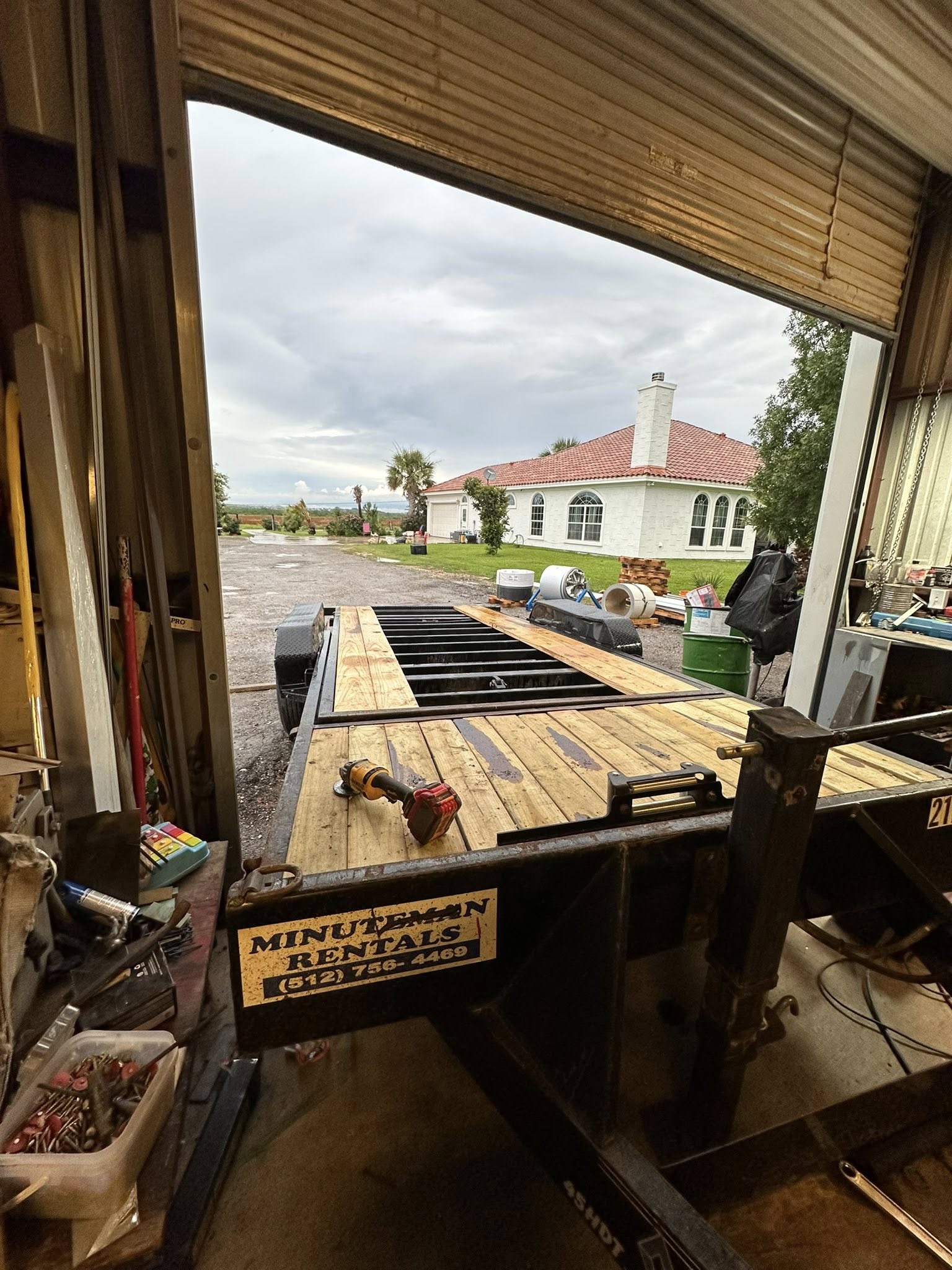 Minuteman Rentals flatbed trailer parked outside shop